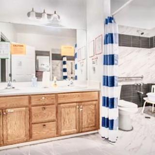 A bright bathroom featuring a wooden vanity with a large mirror, accented by a striped shower curtain and modern fixtures.