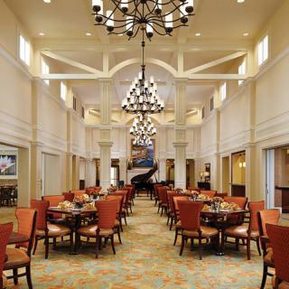 A spacious and elegantly decorated dining room with chandeliers and neatly arranged tables and chairs.