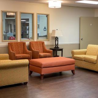 A cozy living room setup featuring colorful seating options including a sofa, two armchairs, and an ottoman.