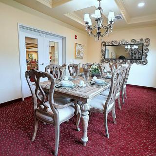 A well-decorated dining room featuring an elegant chandelier, ornate table and chairs, with a stylish mirror on the wall.