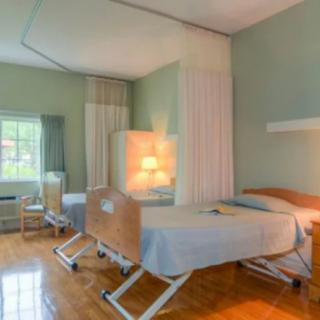 A hospital room with two beds and privacy curtains.