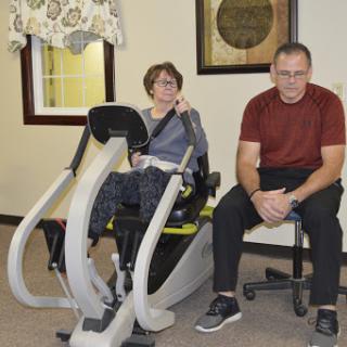 A man and a woman engage in a physical therapy session, utilizing specialized exercise equipment.