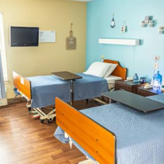 A clean and organized hospital room with two beds and essential medical equipment.