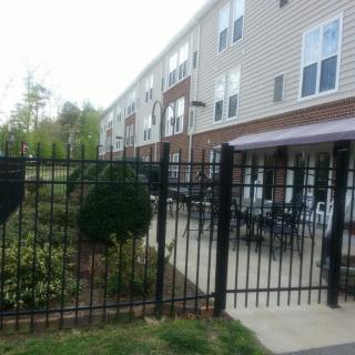 An apartment complex with a fenced patio area and outdoor seating.