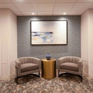 A cozy waiting area with two chairs, a small table, and a piece of abstract artwork on the wall.