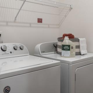 A tidy laundry room with a washing machine, dryer, and essential supplies.