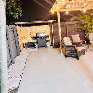 A cozy outdoor patio setup featuring comfortable seating and a grill, illuminated by soft evening lights.