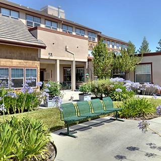 A building exterior with landscaped gardens and benches.