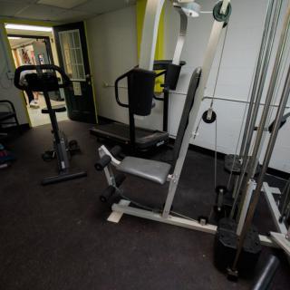 A gym room equipped with various exercise machines and weights.