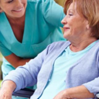 A nurse providing assistance to an elderly woman in a wheelchair.