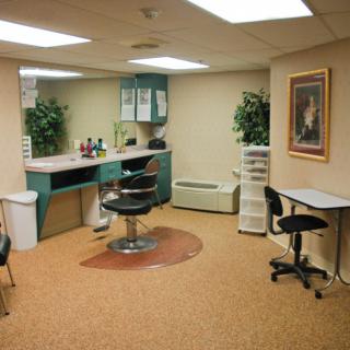 A cozy salon interior featuring a hair cutting station with chairs, mirrors, and decorative plants.