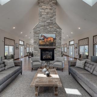 A spacious and modern living room featuring a stone fireplace, sleek sofas, and natural lighting.