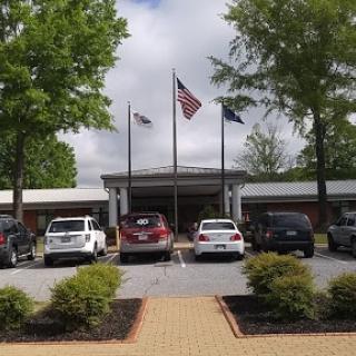 A view of a building with American flags in front, surrounded by trees and parked cars.