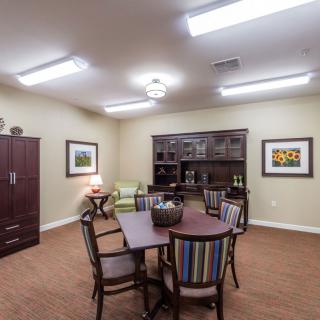 A well-lit office conference room with a round table, chairs, and bookshelves.