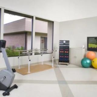 A well-lit gym space equipped with an exercise bike, therapy balls, and a mirror for fitness activities.