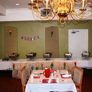 An elegantly set dining area with a buffet setup in the background and a chandelier overhead.