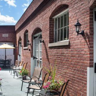 Outdoor patio area with brick walls, chairs, and plants on a sunny day.