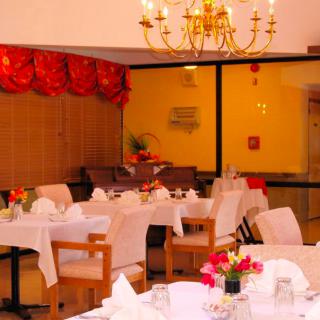 A warmly lit restaurant interior with elegantly set tables and a chandelier.
