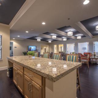 A spacious kitchen with a granite countertop and adjacent dining area, featuring modern lighting and ample seating.
