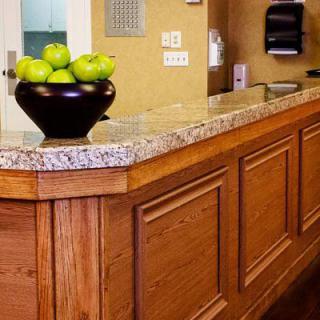 A hotel reception desk with a bowl of green apples.