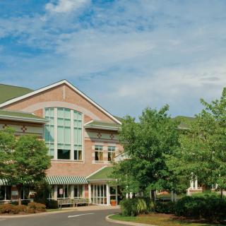 A modern healthcare facility surrounded by trees and under a clear blue sky.