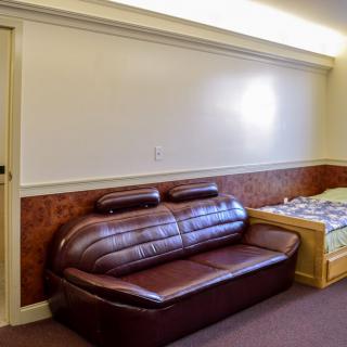 A minimalist room with a brown leather sofa and a bed.
