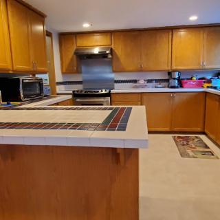 A modern kitchen with wooden cabinets, a central island, and stainless steel appliances.