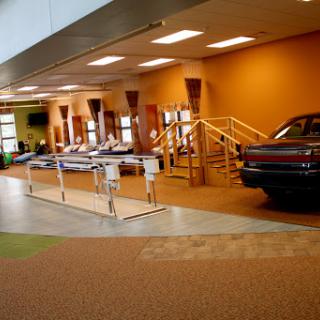 A view of a modern waiting area in a medical facility, featuring comfortable seating and an unusual automobile display.