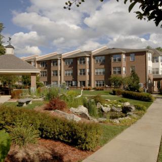 A well-maintained building with a landscaped garden and pathway under a cloudy sky.