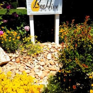 A welcoming sign for BeeHive surrounded by vibrant flowers and landscaping.