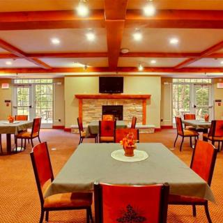 A spacious dining room featuring several tables and chairs, with a central fireplace and warm lighting.