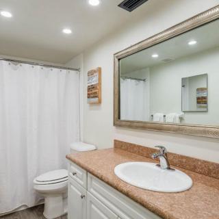 A modern bathroom with a large mirror, countertop sink, and shower curtain.