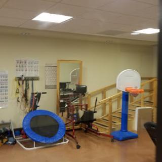 A well-equipped rehabilitation gym featuring a trampoline and a basketball hoop.