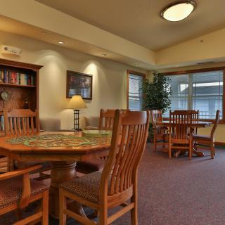 A cozy library reading area with wooden tables and chairs, surrounded by bookshelves.
