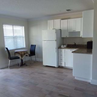A compact kitchen with white cabinets and a small dining area featuring a table and two chairs next to a window.