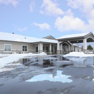 A building with a snow-covered roof and driveway on a cloudy winter day.