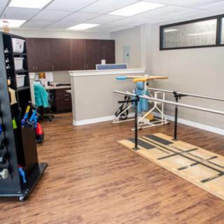A well-equipped rehabilitation room with parallel bars and exercise equipment.