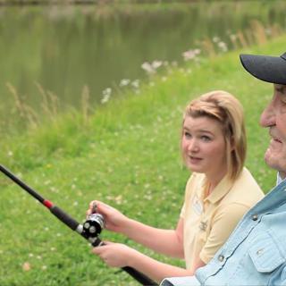 A young woman and an older man enjoying a fishing trip by the lake.