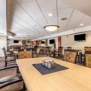 A spacious and modern dining area with multiple tables and chairs, featuring elegant lighting and televisions on the walls.