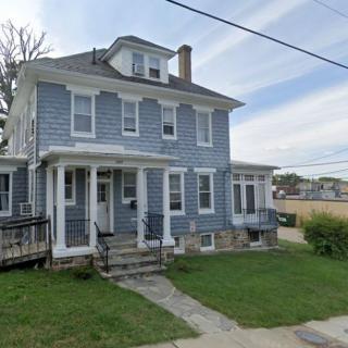 A two-story house with a porch and a neatly maintained lawn.