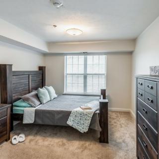 A neatly arranged bedroom with a bed, dresser, and window providing natural light.