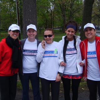 A group of people poses together outdoors wearing casual clothing and hats.