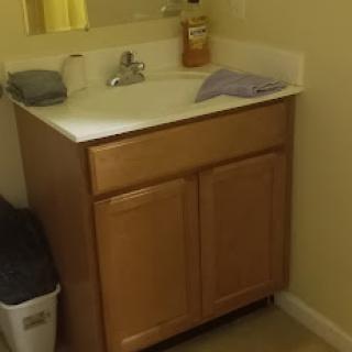 A simple bathroom sink area featuring a wooden vanity and essential items.