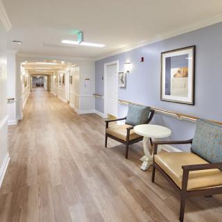 A clean and well-lit hallway in a healthcare facility with seating and artwork on the walls.