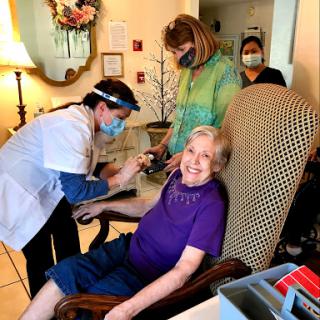 Healthcare workers assist an elderly resident during a vaccination event.