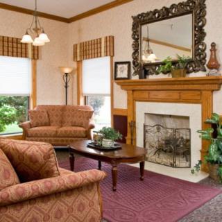 A cozy living room featuring a sofa, coffee table, fireplace, and a large mirror.