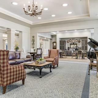 A spacious and elegantly designed living room with comfortable seating, a chandelier, and a grand piano.