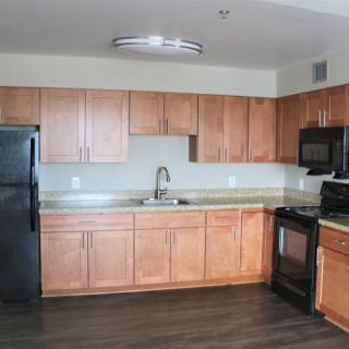 A modern kitchen with wood cabinets and sleek appliances.