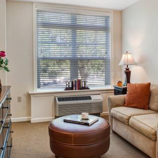 A cozy living room with a sofa, lamp, and coffee table by the window.