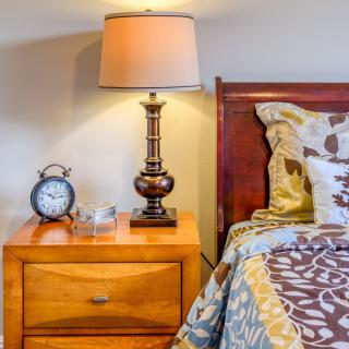 A cozy bedroom setting with a bedside table, lamp, and alarm clock.